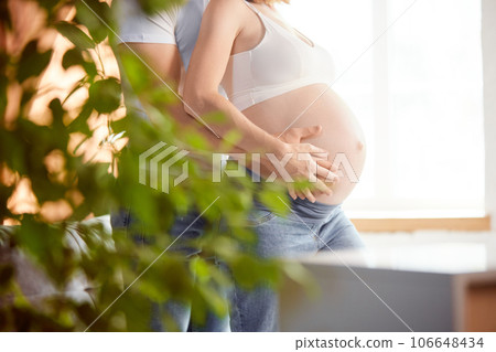 Future parents. Cropped image of male and female hands on pregnant woman's belly. Young couple expecting baby Future parents. Cropped image of male and female hands on pregnant woman's belly. Young couple expecting baby 106648434