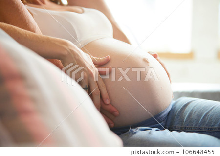 Future parents. Cropped image of male and female hands on pregnant woman's belly. Young couple expecting baby Future parents. Cropped image of male and female hands on pregnant woman's belly. Young couple expecting baby 106648455