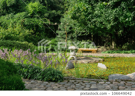 stone lantern on a small island in the middle of a pond in a Japanese garden 106649042