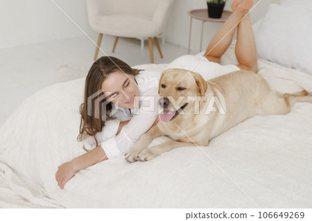 girl in white clothes with dog labrador playing at home 106649269