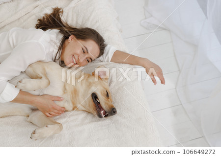 girl in white clothes with dog labrador playing at home girl in white clothes with dog labrador playing at home 106649272