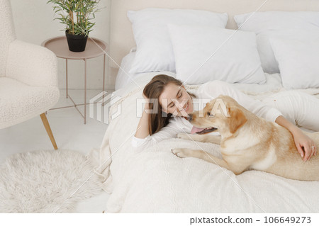 girl in white clothes with dog labrador playing at home 106649273