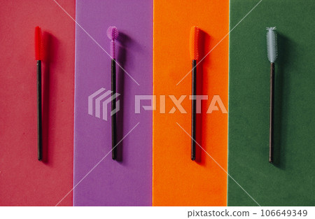 Set of multicolored silicone mascara brushes on a multicolored bright background. Green, pink, purple, orange lash brushes. Modern decorative cosmetics for women. Female beauty and glamour fashion. 106649349