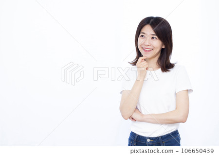 A woman in her thirties thinking with a smile in front of a white background A woman in her thirties thinking with a smile in front of a white background 106650439
