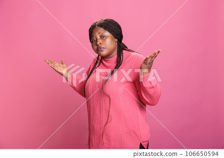 Doubtful young adult raising shoulder and being uncertain about answer, doing i dont know sign over pink background. Clueless indecisive model expressing confusion having unknown expression 106650594