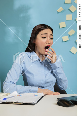 Corporate female employee working overtime in modern office, trying to meet project deadline. Professional woman exhausted by extra workload sitting at modern office desk. Corporate female employee working overtime in modern office, trying to meet project deadline. Professional woman exhausted by extra workload sitting at modern office desk. 106650632