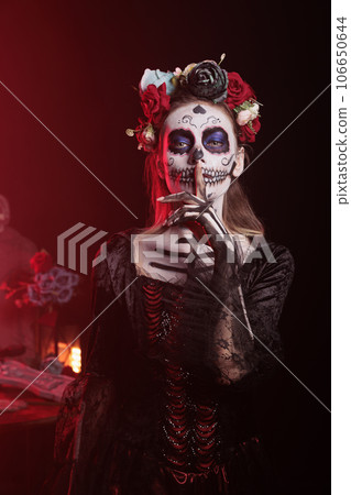 Spooky horror model doing hush sign to keep secret, wearing santa muerte halloween costume and showing slience mute and secrecy gesture with finger over lips, holy dios de los muertos. Spooky horror model doing hush sign to keep secret, wearing santa muerte halloween costume and showing slience mute and secrecy gesture with finger over lips, holy dios de los muertos. 106650644