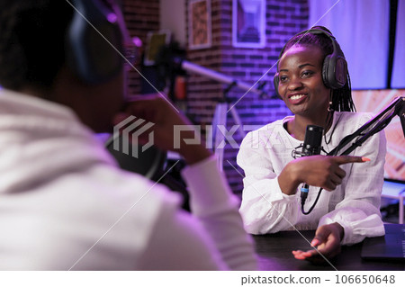 Online show host enjoying chat with african american woman sharing investment advice during business focused podcast. Talking show interviewer in home studio broadcasting interview live Online show host enjoying chat with african american woman sharing investment advice during business focused podcast. Talking show interviewer in home studio broadcasting interview live 106650648