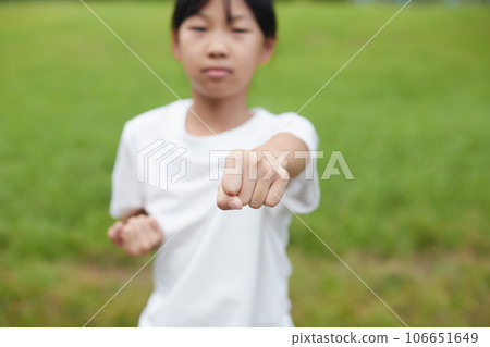 Elementary school girl practicing karate in a midsummer park Elementary school girl practicing karate in a midsummer park 106651649