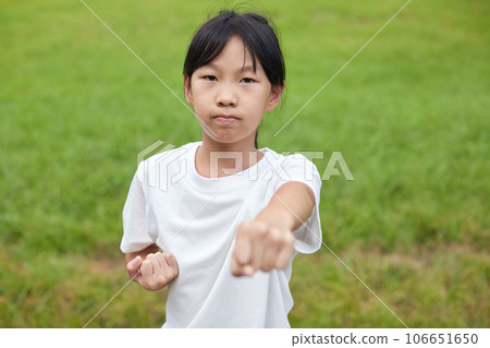 Elementary school girl practicing karate in a midsummer park Elementary school girl practicing karate in a midsummer park 106651650