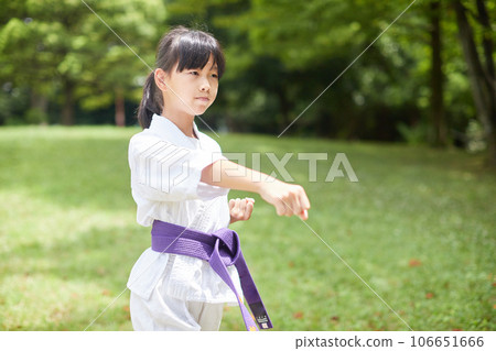 Elementary school girl practicing karate in a midsummer park Elementary school girl practicing karate in a midsummer park 106651666