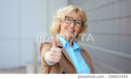 Positive female worker shows thumb up approving work Positive female worker shows thumb up approving work 106652493