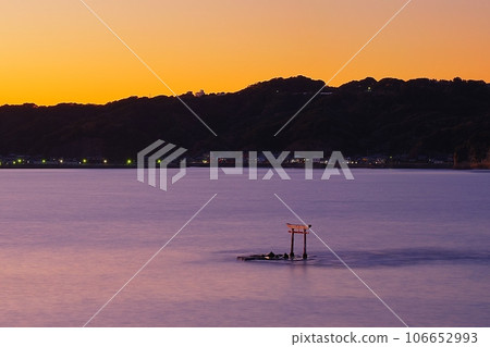 Katsuura Bay and the underwater torii gate of the former Tomisaki Shrine against a golden sunset sky 106652993