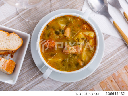 Served Galician pot, thick hot soup made from different types of meat and vegetables. Served Galician pot, thick hot soup made from different types of meat and vegetables. 106653482