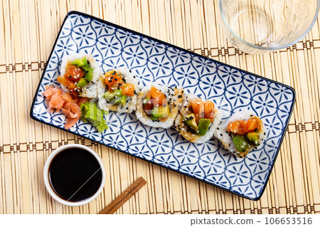 On blue and white plate there is Saketaki roll of crab, avocado, cucumber and salmon On blue and white plate there is Saketaki roll of crab, avocado, cucumber and salmon 106653516
