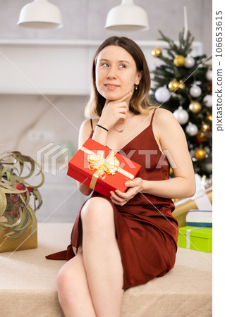 Cheerful woman poses against the background of a Christmas tree Cheerful woman poses against the background of a Christmas tree 106653615
