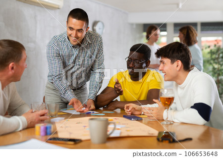 Positive man playing board game with male friends Positive man playing board game with male friends 106653648