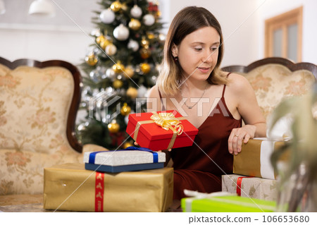 Happy young woman prepares Christmas presents Happy young woman prepares Christmas presents 106653680