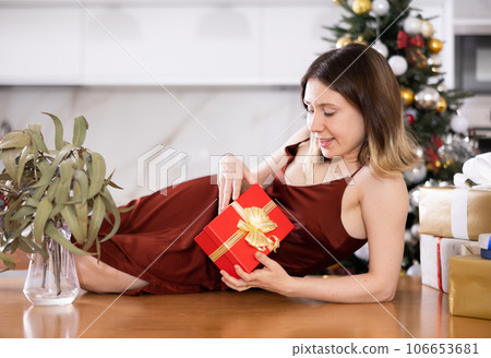 Woman poses with Christmas presents at home 106653681