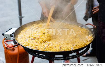 Preparation of Catalan seafood fideua in paellera on street festival Preparation of Catalan seafood fideua in paellera on street festival 106653871