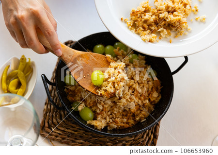 Female hands portioning Migas del pastor with grapes into plates 106653960