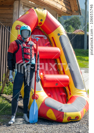 A mannequin in a red life jacket next to an inflatable boat as an advertisement for rafting or boating on the river in tourist places. 106655746