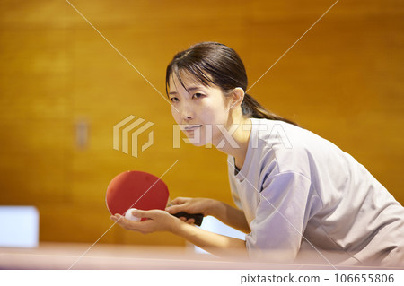 一名女子在體育館的乒乓球檯前準備發球。 一名女子在體育館的乒乓球檯前準備發球。 106655806