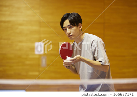 一名男大學生在體育館的乒乓球檯上準備發球。 106657171