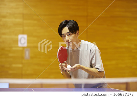 一名男大學生在體育館的乒乓球檯上準備發球。 106657172