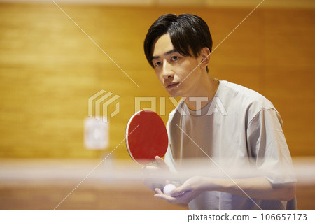 一名男大學生在體育館的乒乓球檯上準備發球。 一名男大學生在體育館的乒乓球檯上準備發球。 106657173