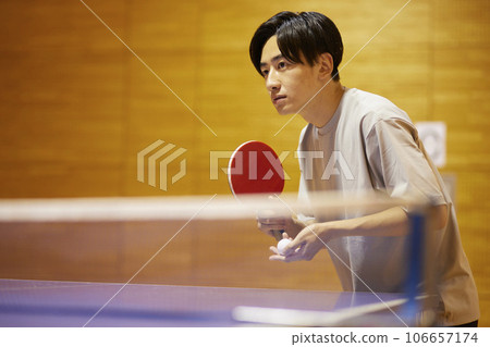一名男大學生在體育館的乒乓球檯上準備發球。 一名男大學生在體育館的乒乓球檯上準備發球。 106657174
