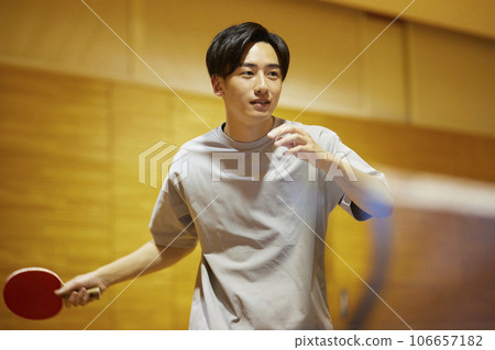 年輕的大學生在體育館練習乒乓球技巧。 年輕的大學生在體育館練習乒乓球技巧。 106657182