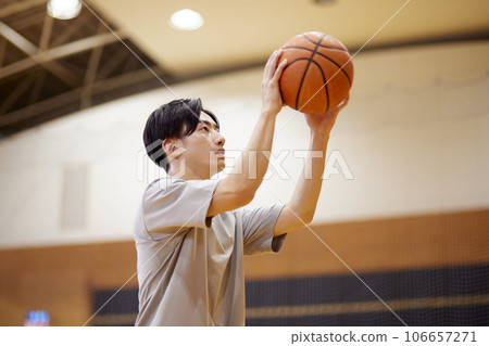 A male college student training alone on the gymnasium court. 106657271