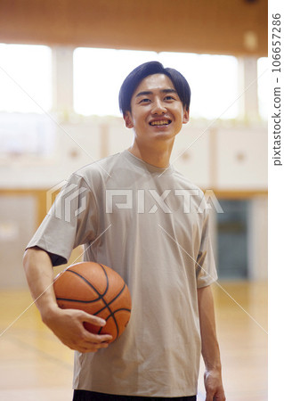 Japanese male university student practicing basketball in the gymnasium 106657286