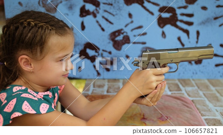 Little girl shoots at shooting range with gun. Outdoors entertainment for tourists in Thailand. Active leisure on vacation, traveling in Asia. Practice in shooting gallery safe legal pistol weapons. Little girl shoots at shooting range with gun. Outdoors entertainment for tourists in Thailand. Active leisure on vacation, traveling in Asia. Practice in shooting gallery safe legal pistol weapons. 106657821