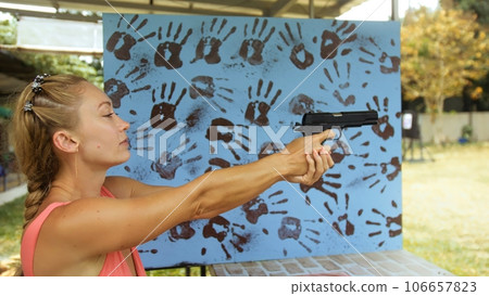 Woman shoots at shooting range with pneumatic gun. Outdoors entertainment for tourists in Thailand.Active leisure on vacation, traveling in Asia.Practice in shooting gallery safe legal pistol weapons. Woman shoots at shooting range with pneumatic gun. Outdoors entertainment for tourists in Thailand.Active leisure on vacation, traveling in Asia.Practice in shooting gallery safe legal pistol weapons. 106657823