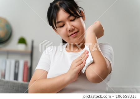 Woman wipes cleaning her arm with a tissue paper towel. Healthcare and medical concept. Woman wipes cleaning her arm with a tissue paper towel. Healthcare and medical concept. 106658315