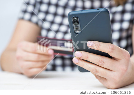 Womans hands hold credit card and use smartphone to shop online. Online shopping 106661856