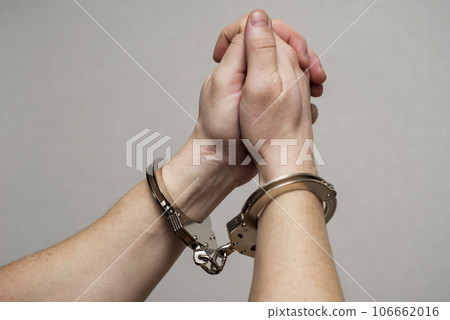 Handcuff on mans arms, praying for forgiveness. 106662016