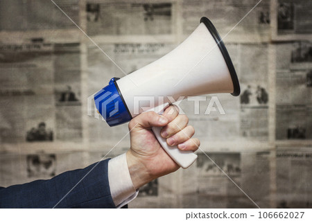 A man holding a megaphone on background of newspapers. News message concept A man holding a megaphone on background of newspapers. News message concept 106662027