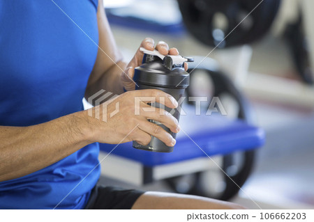 Middle-aged man trying to drink protein after training at the gym 106662203