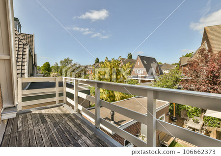 a balcony with some trees and houses in the background, as seen from an apartment's roof decking area 106662373