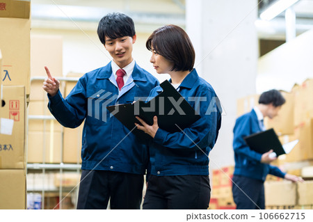 Male and female employees wearing work clothes working at a distribution center 106662715