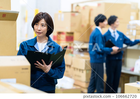 Male and female employees wearing work clothes working at a distribution center Male and female employees wearing work clothes working at a distribution center 106662720