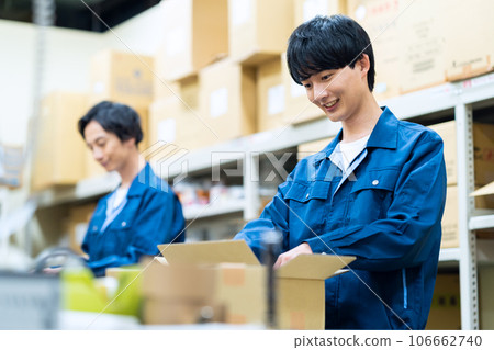 A young male worker wearing work clothes working at a distribution center 106662740