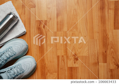 New light blue green female running shoes metal water bottle and towel on emty wooden floor. Stylish monochrome shoes for active people that incorporate new health technology. Top view 106663433