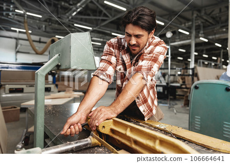 Young carpenter working on woodworking machines in the furniture factory 106664641