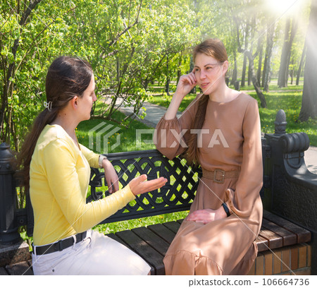 Two girls talking in the park 106664736