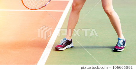 Legs of young girl in a closed tennis court with racket, sport shoes 106665891