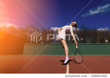 Sexy girl tennis player holding tennis racket on the court. Young woman is playing tennis. 106665892